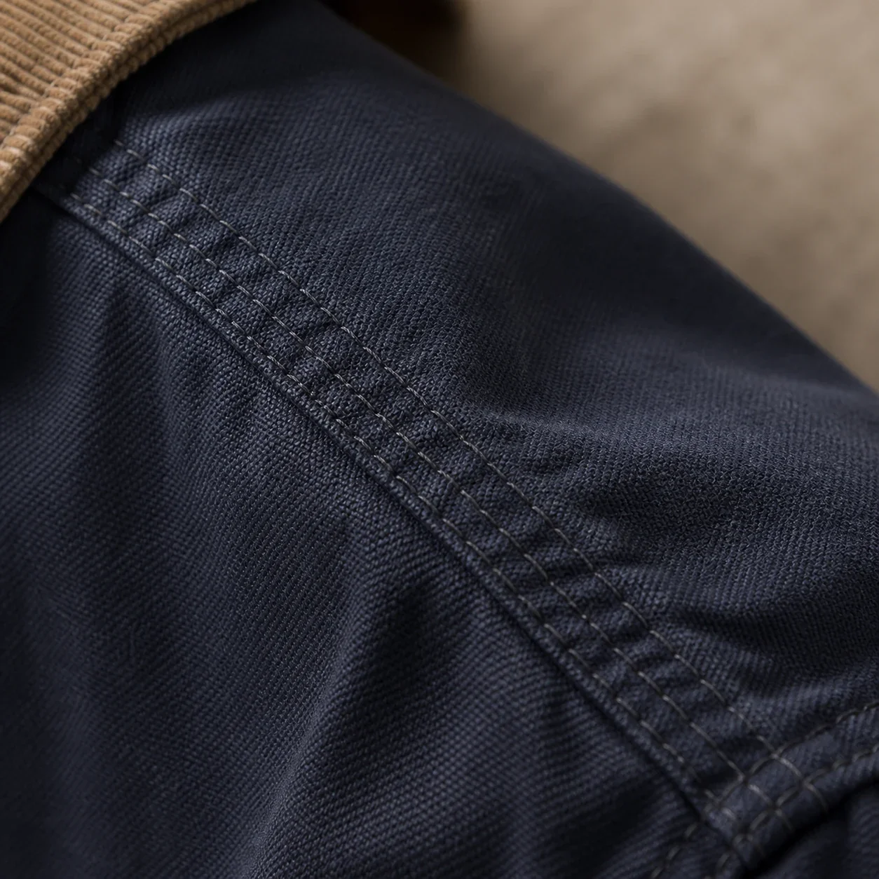 Macro view of three parallel load-bearing seams in deep navy canvas